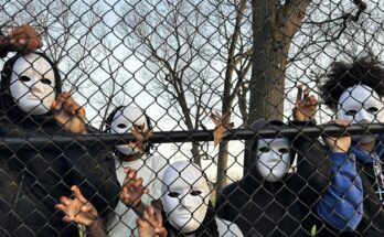 A migrant family poses with masks on behind a gate.