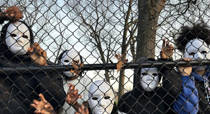 A migrant family poses with masks on behind a gate.