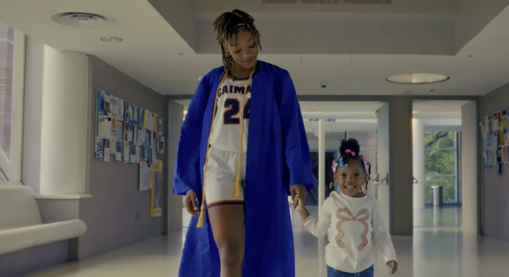 A still from a CUNY commercial showing a graduate holding hands with a child.