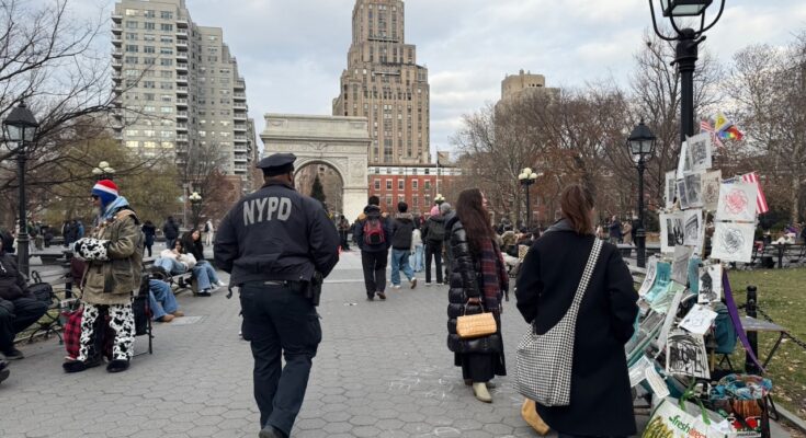 A NYPD officer walks in Washington Square Park.